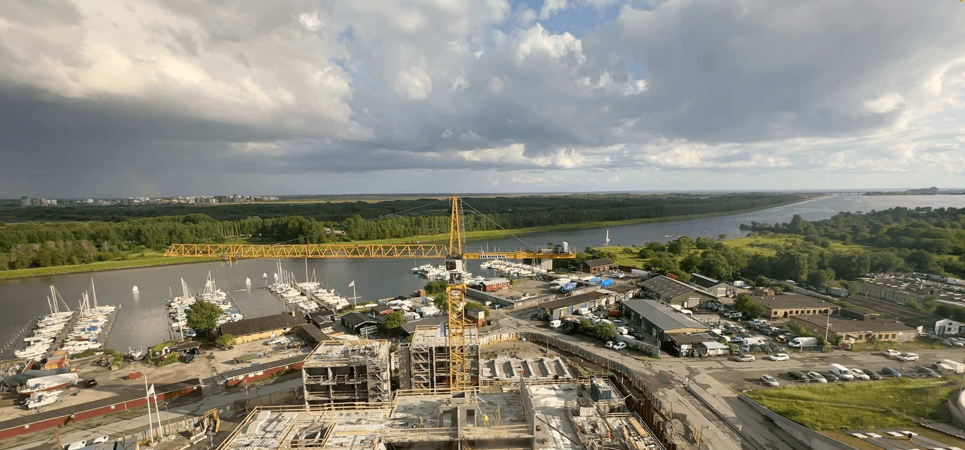 Kranfører betjener tårnkran på dansk byggeplads ved solopgang